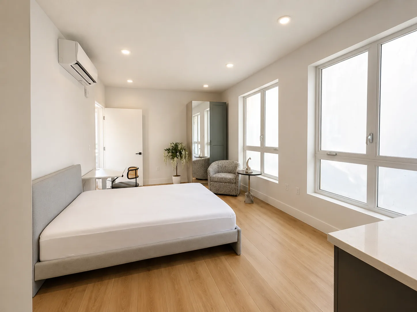 Actual Unit 202 standard private bedroom with bed, desk, seating, and bright windows